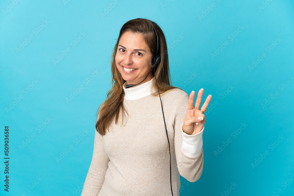 Fototapeta premium Young telemarketer woman over isolated blue background happy and counting three with fingers