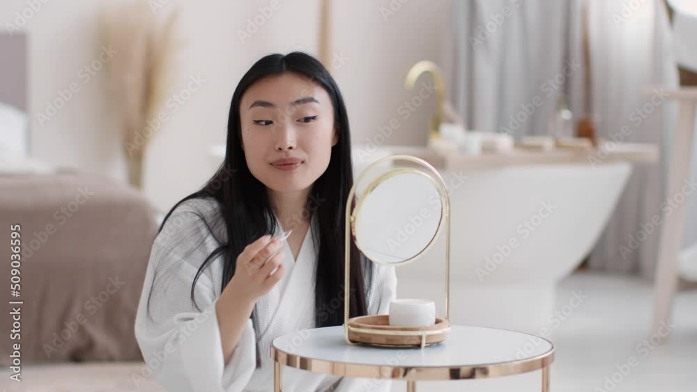 Oral hygiene. Young pretty asian lady in bathrobe cleaning her teeth with teeth floss stick, slow motion, free space Oral hygiene. Young pretty asian lady in bathrobe cleaning her teeth with teeth floss stick, slow motion, free space