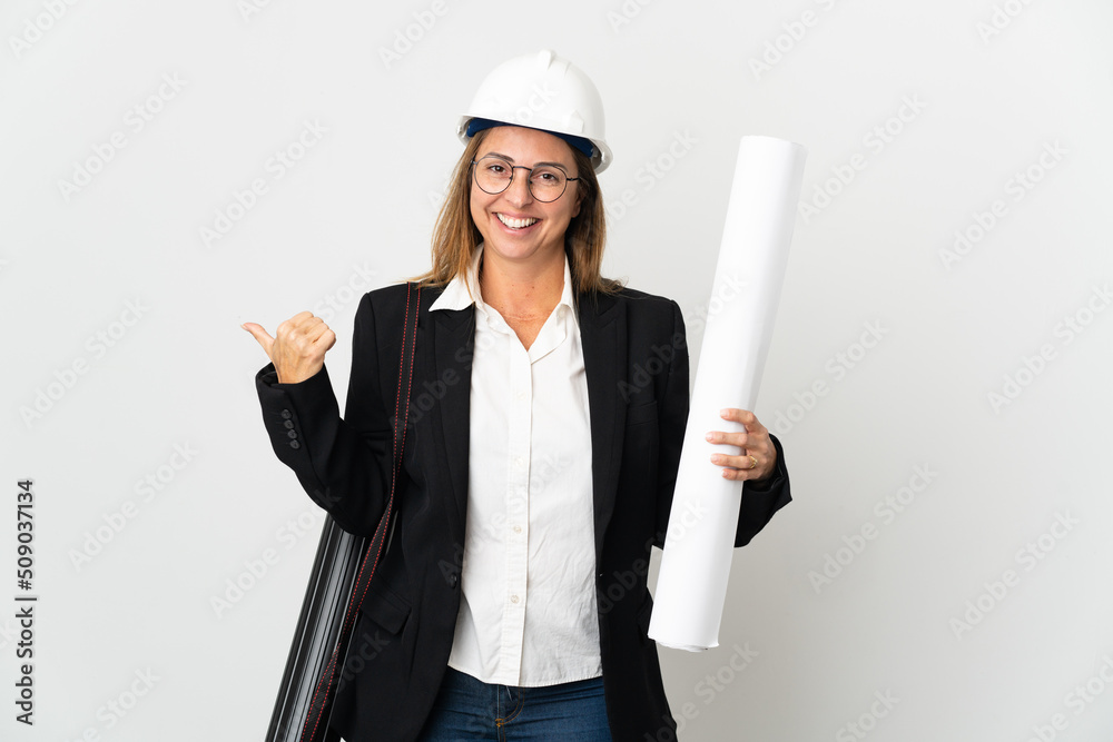 Middle age architect woman with helmet and holding blueprints over isolated background pointing to the side to present a product Middle age architect woman with helmet and holding blueprints over isolated background pointing to the side to present a product