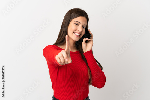 Teenager Brazilian girl using mobile phone over isolated white background showing and lifting a finger