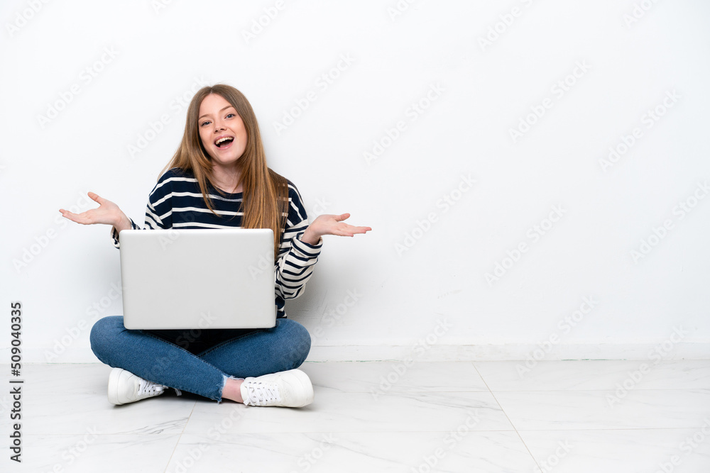 Young caucasian woman with a laptop sitting on the floor isolated on white background with shocked facial expression Young caucasian woman with a laptop sitting on the floor isolated on white background with shocked facial expression