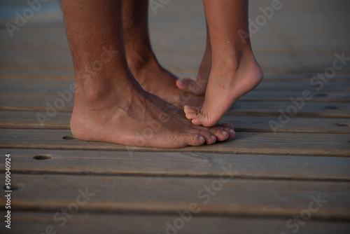 child standing on father's feet