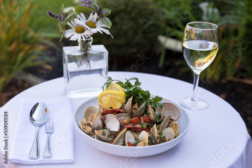 A clam and pasta dish with wine in outdoor setting