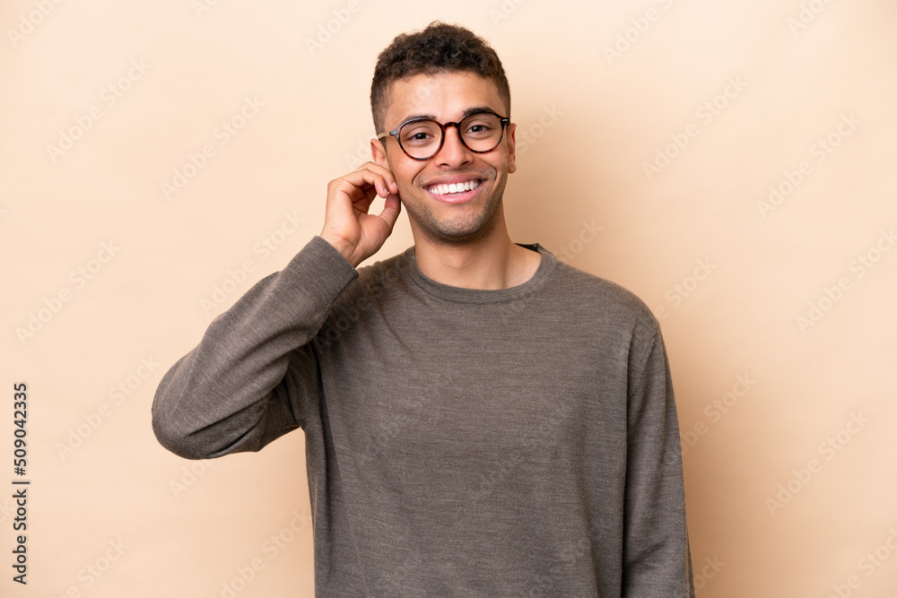 Young Brazilian man isolated on beige background laughing Young Brazilian man isolated on beige background laughing