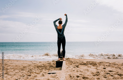 man zipping up his wetsuit at the beach ready to swim in the sea photo