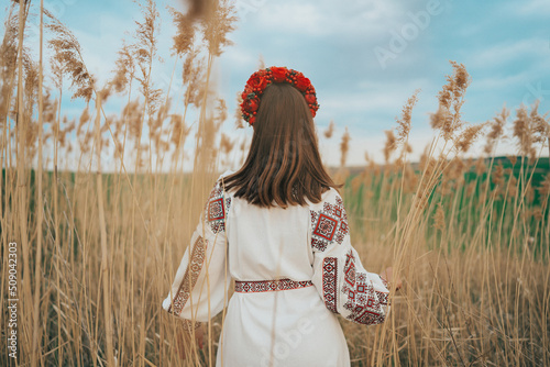 Back view of ukrainian woman in vyshivanka dress on nature background. photo