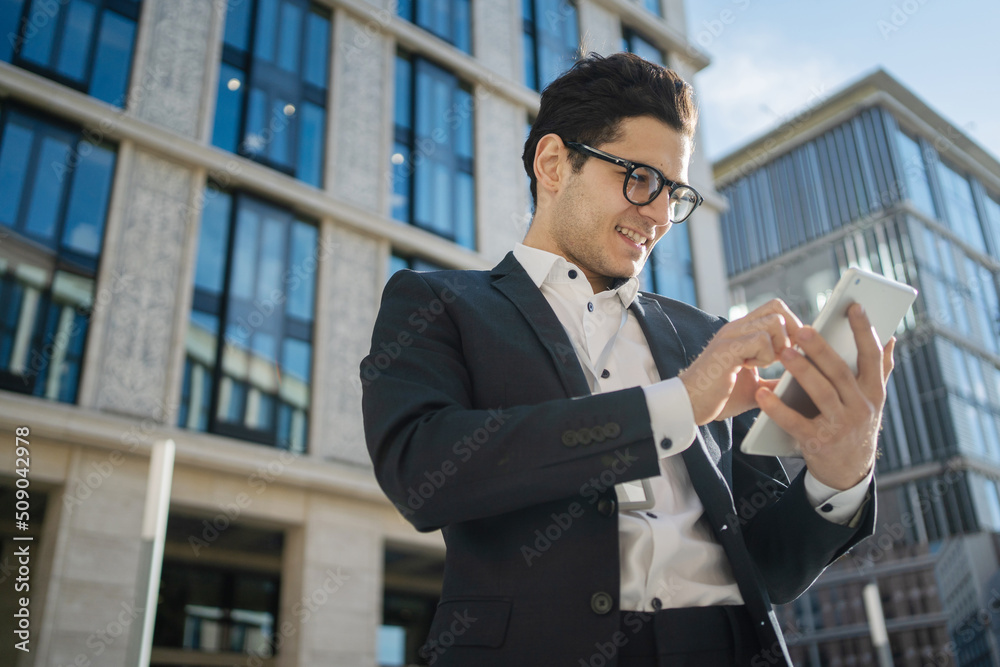 An entrepreneur with glasses uses a tablet responds to a client's letter goes to the office An entrepreneur with glasses uses a tablet responds to a client's letter goes to the office