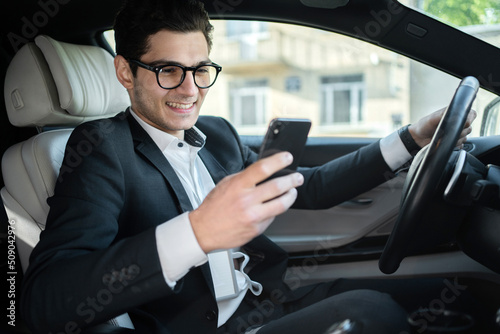 Uses the phone in the car businessman man in a business suit goes to work in the office © muse studio