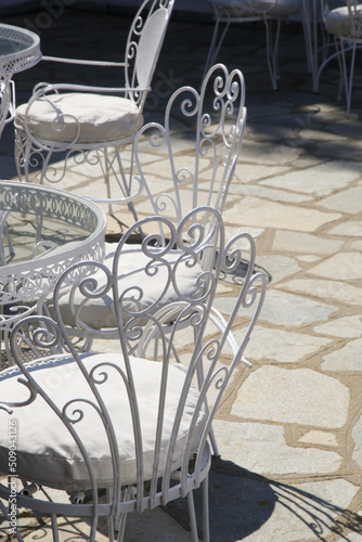 Vintage retro metal outdoor white chairs on stone tiles floor.