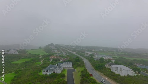 Fly above luxury residential urban borough on city outskirts. Houses along road surrounded by green vegetation. Port Elisabeth, South Africa