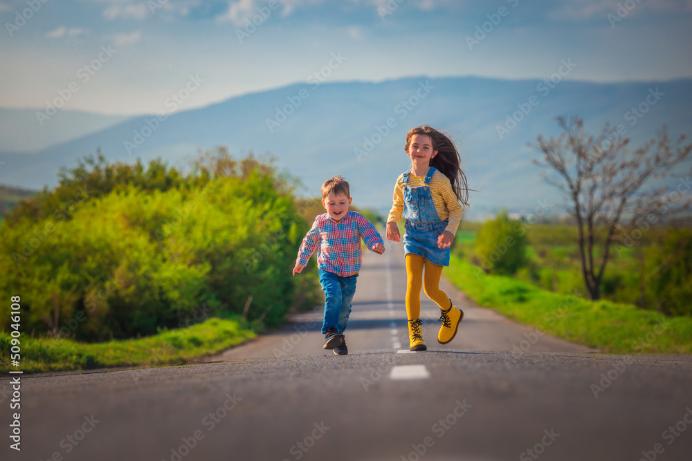 Happy kids brother and sister running on the road in the countryside. Happiness, freedom and childhood concept. Happy kids brother and sister running on the road in the countryside. Happiness, freedom and childhood concept.
