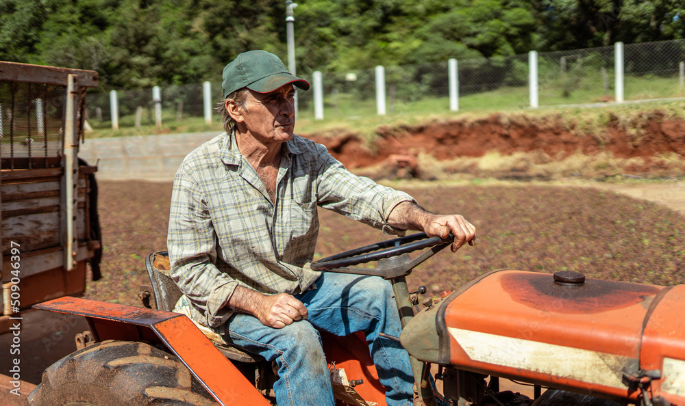 Latin farmer with a hat driving tractor on the farm.