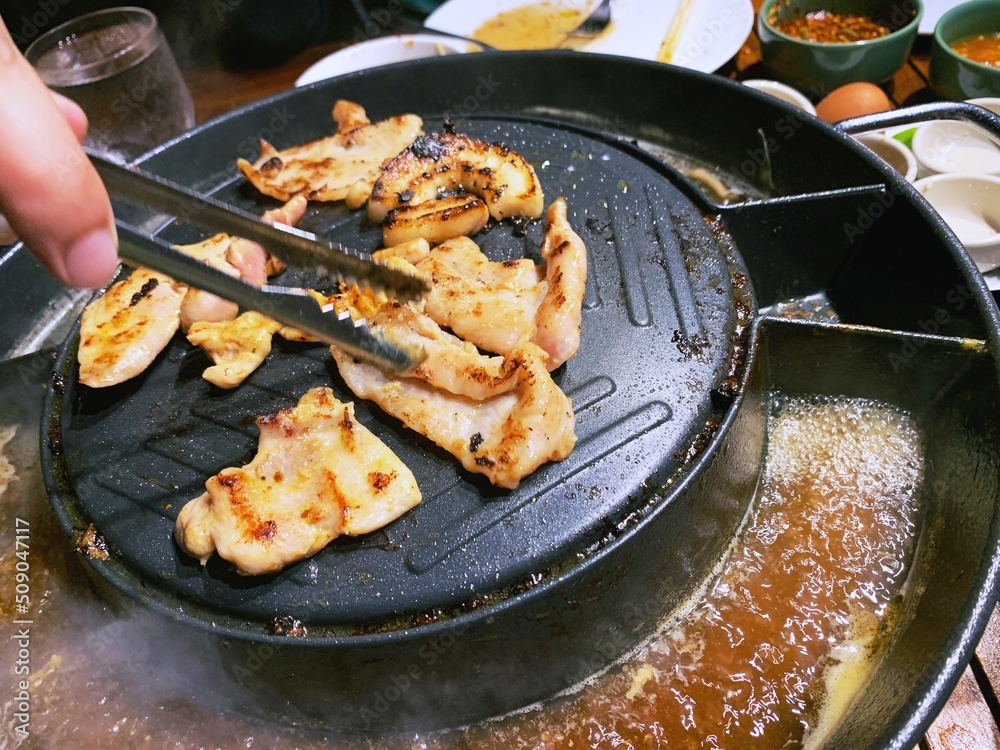 grill pork on hot pan plate. Japanese or Korean Cuisine Jingisukan or Yakiniku barbecue. Thai traditional barbecue roasted buffet. Enjoy eating lifestyle concept. grill pork on hot pan plate. Japanese or Korean Cuisine Jingisukan or Yakiniku barbecue. Thai traditional barbecue roasted buffet. Enjoy eating lifestyle concept.