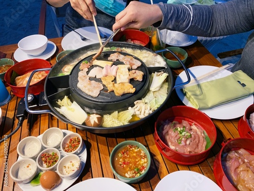 grill pork on hot pan plate. Japanese or Korean Cuisine Jingisukan or Yakiniku barbecue. Thai traditional barbecue roasted buffet. Enjoy eating lifestyle concept. photo