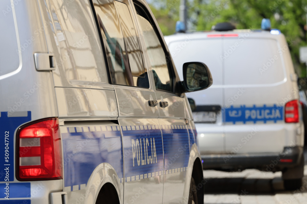 Radiowóz polskiej policji w mieście podczas patrolu na sygnale alarmowym.  - obrazy, fototapety, plakaty 