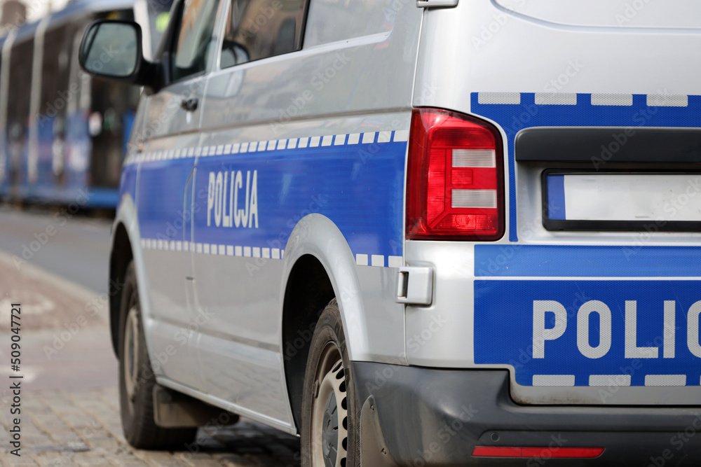 Radiowóz polskiej policji w mieście podczas patrolu na sygnale alarmowym.  - obrazy, fototapety, plakaty 