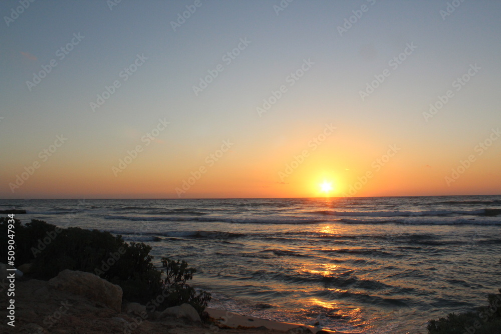 Sunset at Tulum beach with Caribbean Sea on a blue sky day with no clouds on a rocky beach