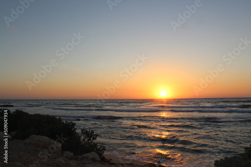 Sunset at Tulum beach with Caribbean Sea on a blue sky day with no clouds on a rocky beach