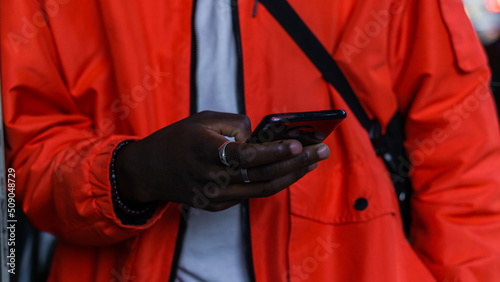 Detail of the hands of an unrecognizable African man holding a cell phone in his hands.