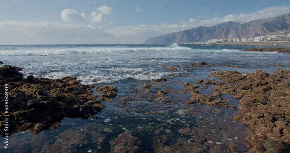 Splashing waves. Black rocky volcanic beach with black lava stones. Puerto de la Santiago, Tenerife. Punta Blanca or Punta Juanita - best place to surf or chill relax. Los Gigantes cliffs. Nobody. Splashing waves. Black rocky volcanic beach with black lava stones. Puerto de la Santiago, Tenerife. Punta Blanca or Punta Juanita - best place to surf or chill relax. Los Gigantes cliffs. Nobody.