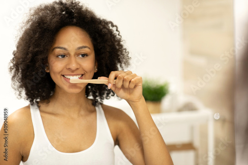 Happy black woman Brushing Teeth With Toothbrush Standing In Bathroom Indoor