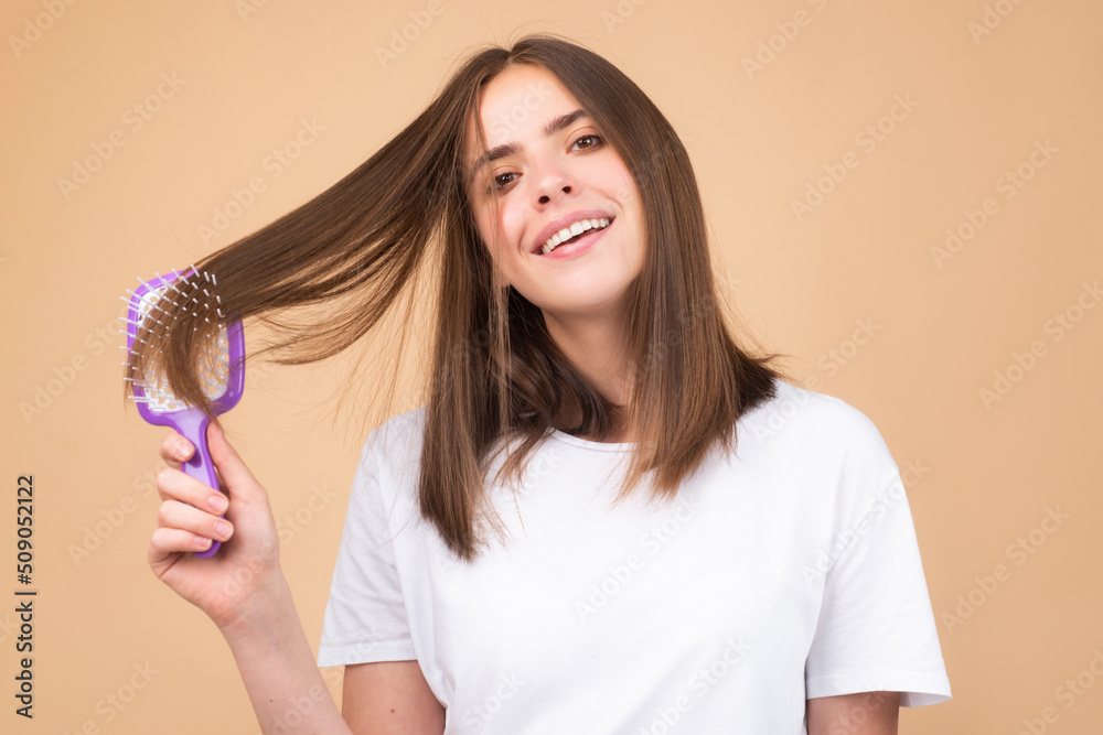 Woman is making hairstyle with comb. Beautiful young woman holding healthy and shiny hair, studio. Woman is making hairstyle with comb. Beautiful young woman holding healthy and shiny hair, studio.