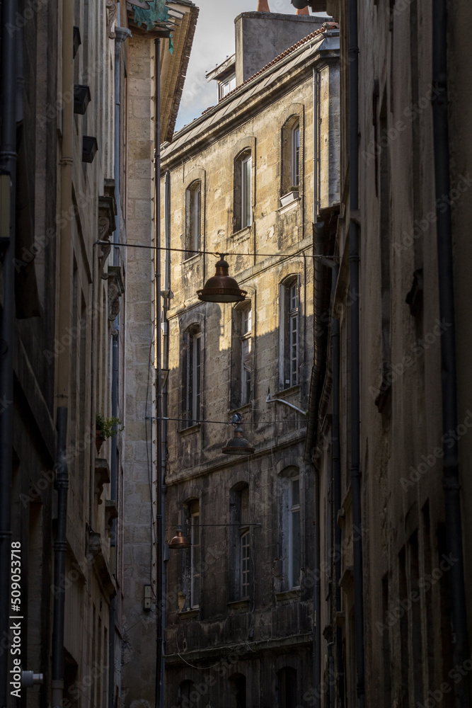Facade of medieval buildings in a dark street, narrow, in the city center of Bordeaux, France. These buildings are typical of the Southwestern French architecture.