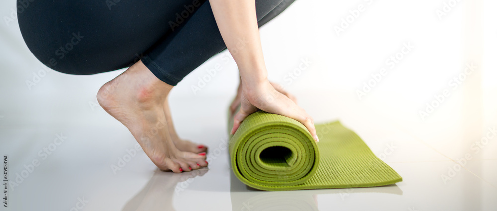 Female hand-rolling green yoga mat for prepare exercise on the mat. Female hand-rolling green yoga mat for prepare exercise on the mat.