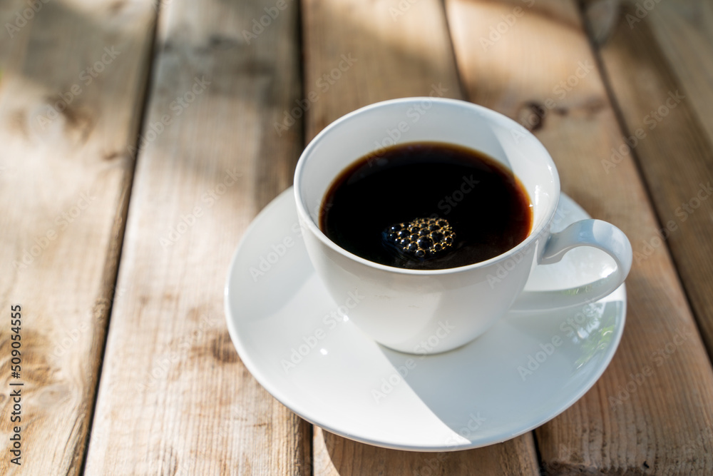 White ceramic coffee cup on the old wooden floor. White ceramic coffee cup on the old wooden floor.