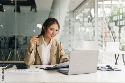 Young beautiful woman using her laptop while sitting in a chair at her working place.