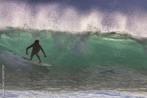 Glorious color of a slow breaking wave resulting in a beautifully backlit aquamarine breaking wave encasulating a silhouetted surfer