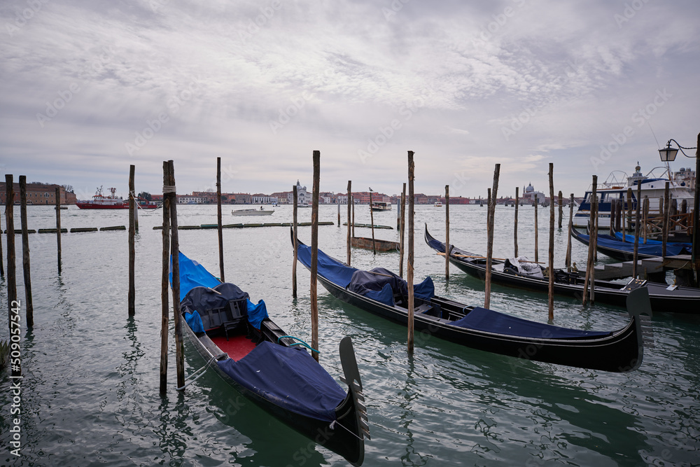 View from Piazza San Marco to Lagoon in Venice. Gondola tied on wooden pole Clouds over Venice
