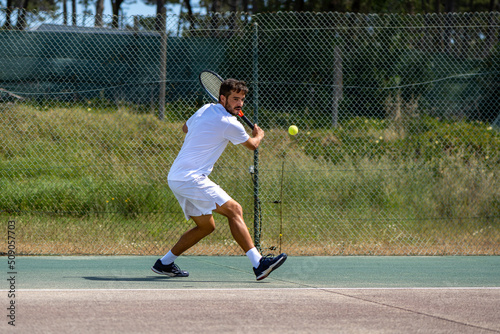 Tennis player hitting backhand at ball photo