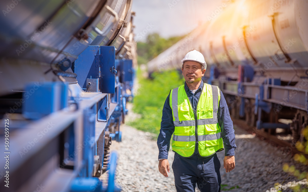 Engineer under inspection and checking construction process railway oil train and checking work on railroad station .Engineer wearing safety uniform and safety helmet in work. Engineer under inspection and checking construction process railway oil train and checking work on railroad station .Engineer wearing safety uniform and safety helmet in work.