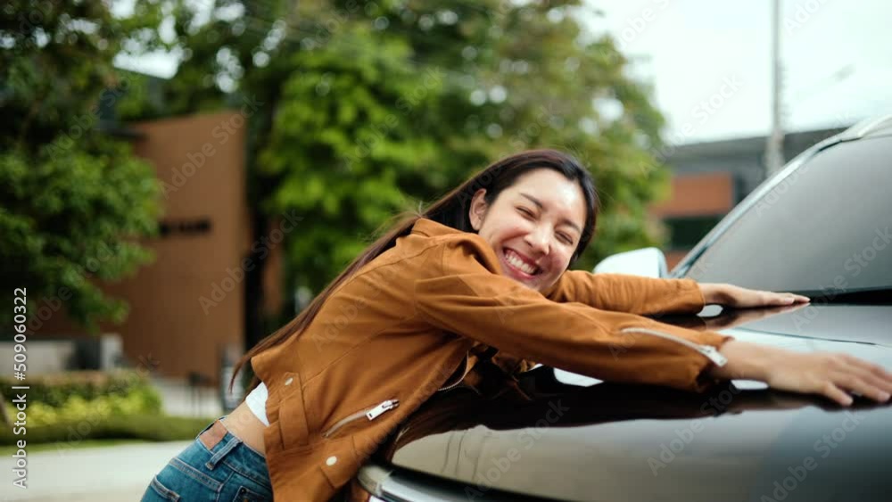 Surprised young asian woman getting the new car. She hugged his car and was very happy. Buy or rent car concept.