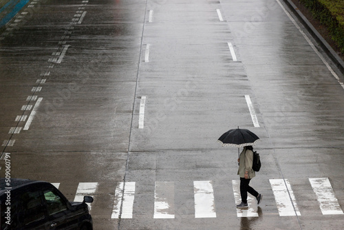 梅雨時期の道路で横断歩道を歩く傘を持っている人々の姿 photo