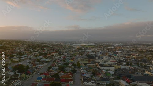 Fly above large town at dusk. Small colourful houses in residential borough and commercial properties. Port Elisabeth, South Africa