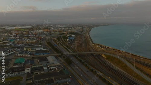 Highway and railway leading along sea coast. Aerial view of transport infrastructure in city at dusk. Port Elisabeth, South Africa