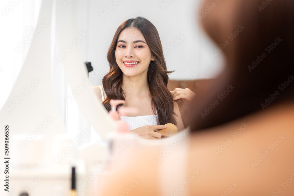 Smiling of young beautiful pretty asian woman clean fresh healthy white skin looking at mirror.asian girl touching on her face with hand and applying cream at home.spa and beauty concept Smiling of young beautiful pretty asian woman clean fresh healthy white skin looking at mirror.asian girl touching on her face with hand and applying cream at home.spa and beauty concept