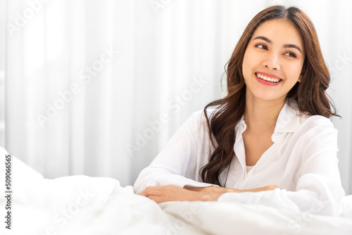 Portrait of smiling cheerful beautiful pretty asian woman clean fresh healthy white skin posing smile in pajamas white clothes.Girl felling relax and enjoy time on the bed at home.asia beauty