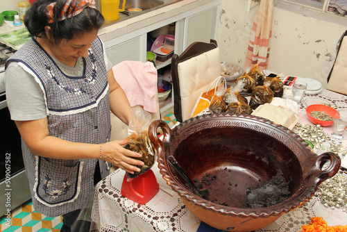 Latin Mexican adult woman prepares packages of freshly made red mole in clay pot to sell and follow the tradition and culture of the Mexican people

