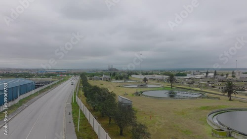 Fly over wastewater treatment circular tanks. Traffic on road leading around. Port Elisabeth, South Africa