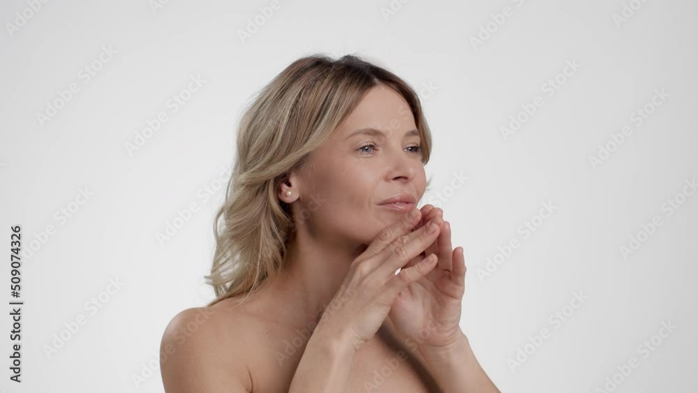 Facebuilding concept. Semi profile portrait of beautiful mature woman doing skin lifting facial massage Facebuilding concept. Semi profile portrait of beautiful mature woman doing skin lifting facial massage