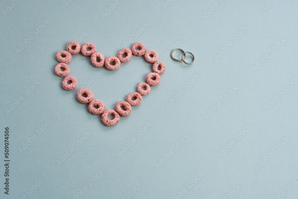 A heart and wedding rings on a colored background. The concept is marriage, love. Love Story. A heart and wedding rings on a colored background. The concept is marriage, love. Love Story.