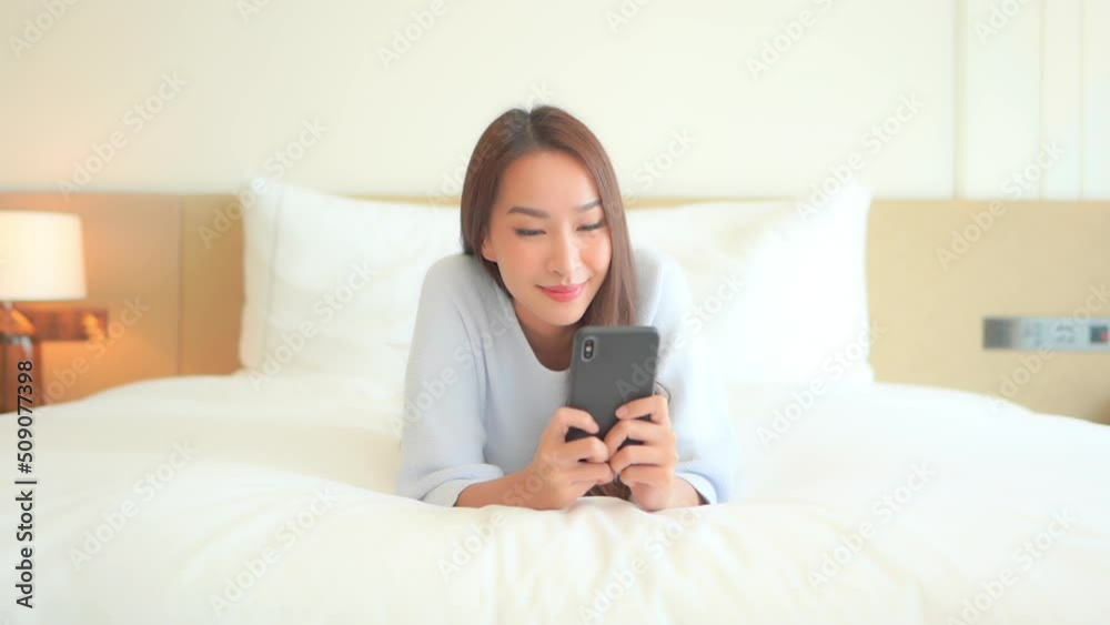 Beautiful Asian Woman Reading Posts on Social Networks With Mobile Phone, Lying on Bed, Slow Motion Beautiful Asian Woman Reading Posts on Social Networks With Mobile Phone, Lying on Bed, Slow Motion