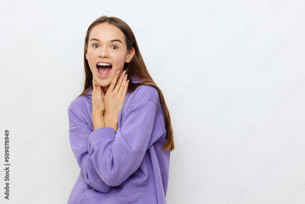 a beautiful woman stands on a white background in a purple tracksuit joyfully presses her hands to her neck, slightly hunched over
