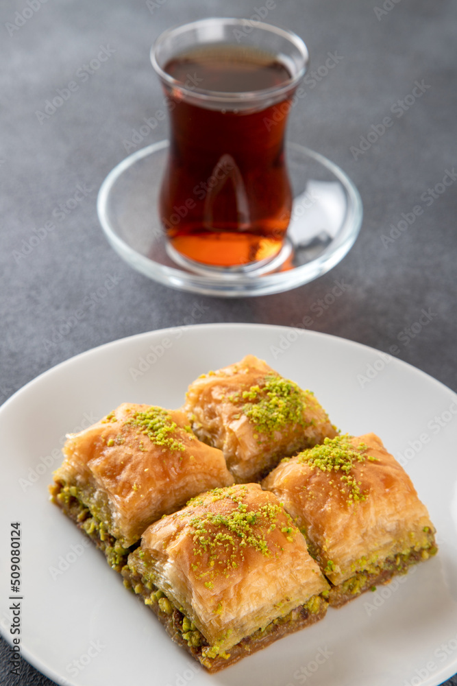 Pistachio baklava on a white plate with Turkish tea
