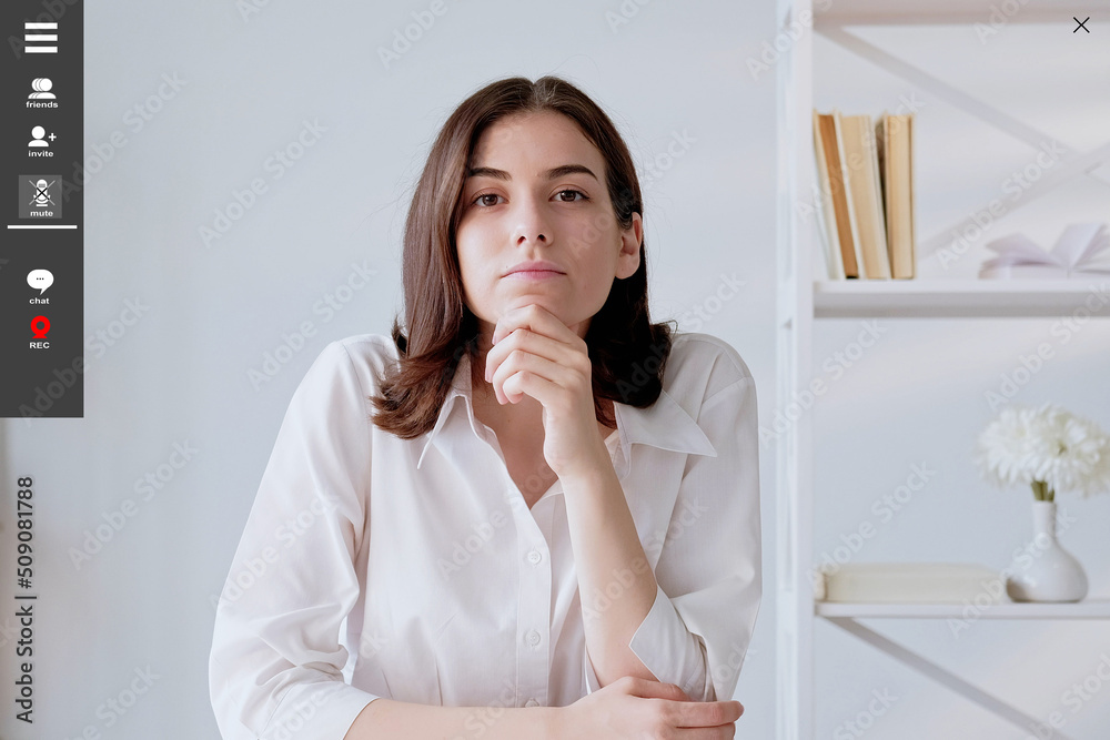 Virtual meeting. Curious woman. Screen mockup. Thoughtful interested lady sitting desk having online conference in light room interior. Virtual meeting. Curious woman. Screen mockup. Thoughtful interested lady sitting desk having online conference in light room interior.