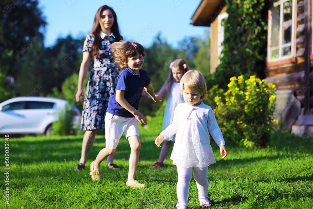 Fototapeta premium Young large family on a summer morning walk. Beautiful mother with children is playing in the park.