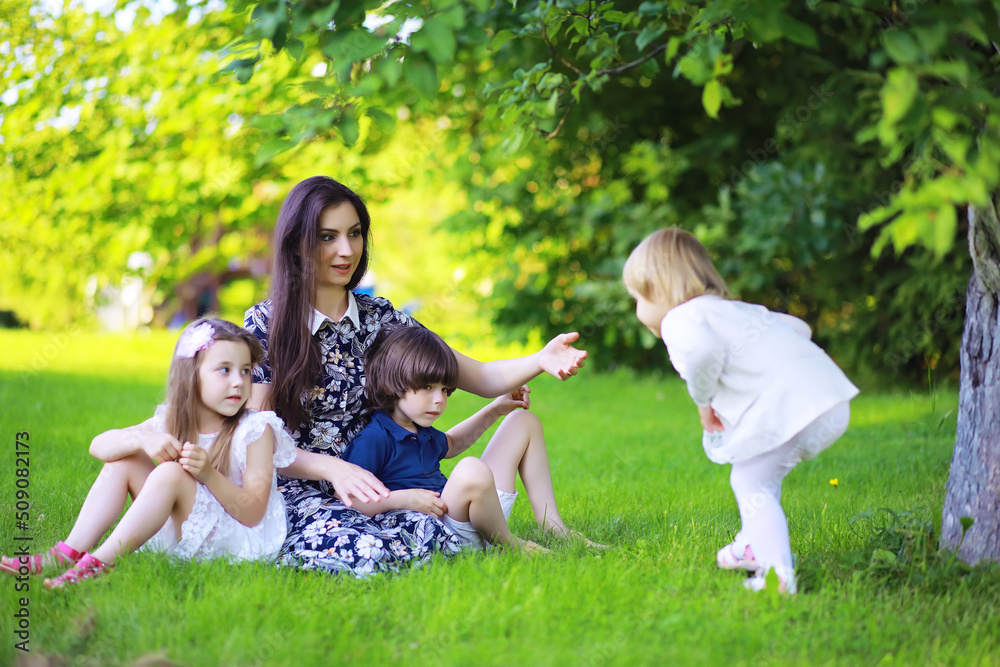 Young large family on a summer morning walk. Beautiful mother with children is playing in the park. Young large family on a summer morning walk. Beautiful mother with children is playing in the park.